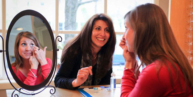 Optician helping a patient insert contact lens